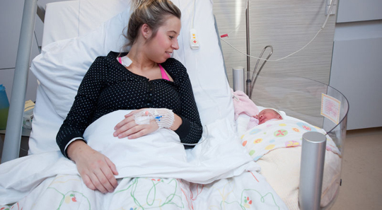 Mother and baby in hospital bed with co-sleeper