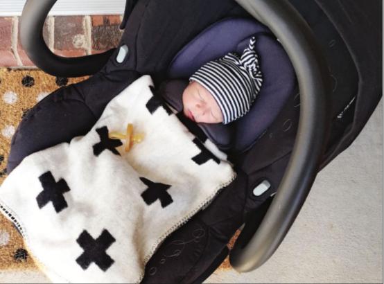 Baby in a carseat with blanket and dummy (pacifier)