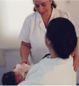 Mother holding baby with smiling hospital midwife