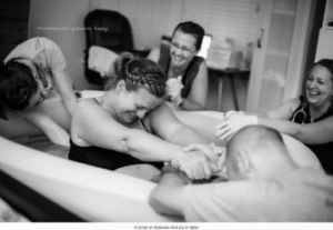 Woman being supported by partner and midwives during labour